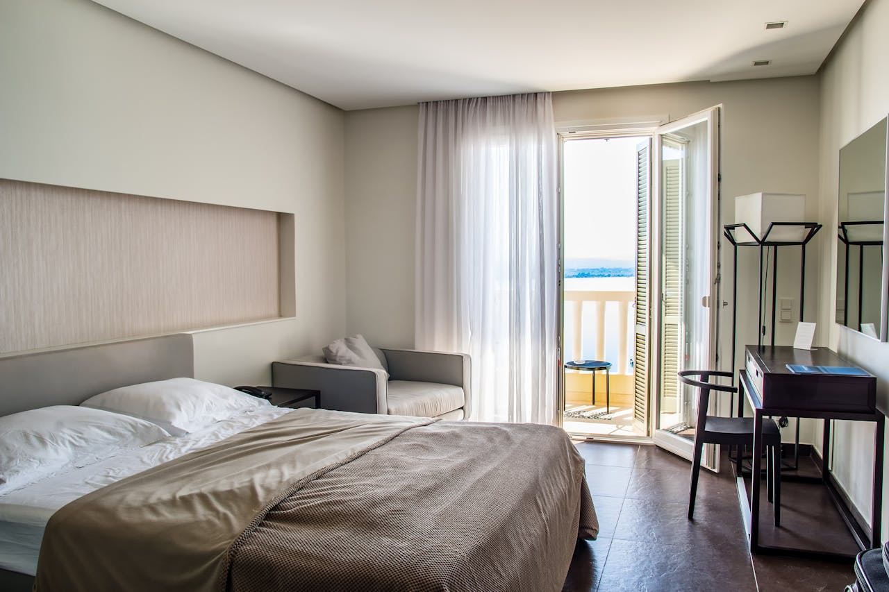 services-03 Spacious, elegantly furnished hotel room featuring a balcony with a sea view and modern amenities.