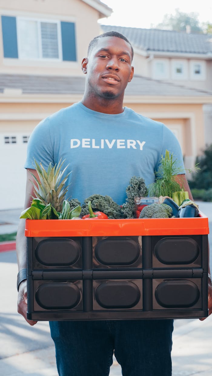 team-04 A delivery man holds a box of fresh produce in a suburban area.