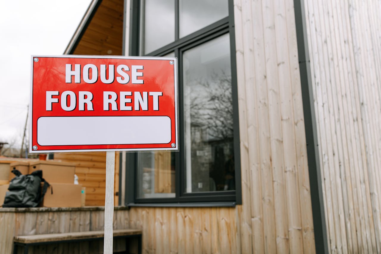journey Red 'House for Rent' sign outside modern wooden house.